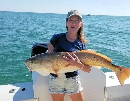 Young lady holding up huge red drum on an Ocracoke fishing charter.